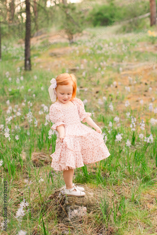 Redhead girl looking at her pink dress in a flower field Redhead girl looking at her pink dress in a flower field