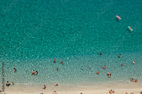 Fototapeta Naklejka Na Ścianę i Meble -  Aerial view of sandy beach with swimming people in sea with transparent blue water in summer.