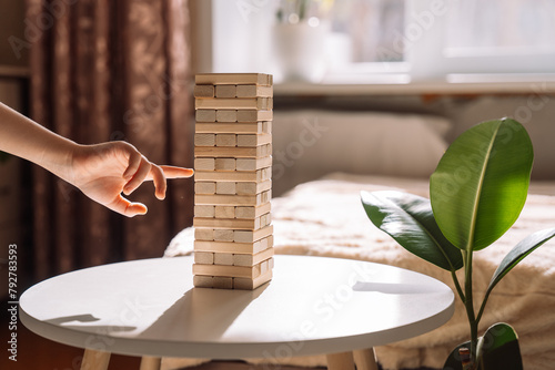 Child slides wooden block of Jenga game. photo