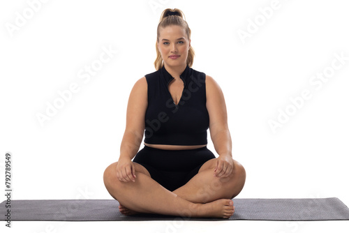 A young Caucasian plus-size model sits cross-legged on yoga mat, white background, copy space