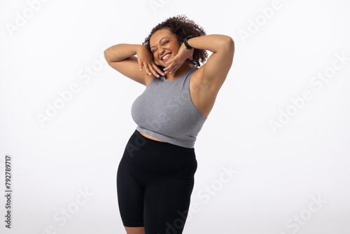 Biracial plus size young female model poses, hands on head, smiling, white background, copy space