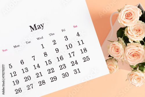 Flat lay of May 2024 paper desk calendar, top view. Pale delicate roses on beige background.