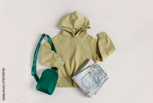 Green  hoodie with jeans and green bag. Mockup on the white background. Template sweatshirt front for design and print. Fashion outfit, casual style. Stylish basic famale clothes.