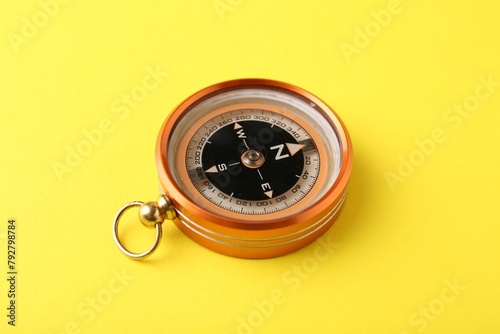 One compass on yellow background, closeup. Tourist equipment