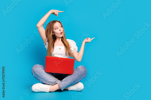 Full size photo of nice young girl indicate fingers empty space ad wear top isolated on blue color background