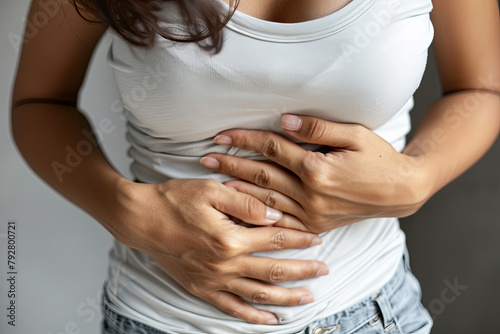 A woman experiencing abdominal discomfort, clutching her stomach photo
