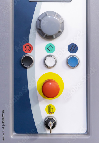 Grey control panel with big red button and other buttons and switches for machinery operation in production