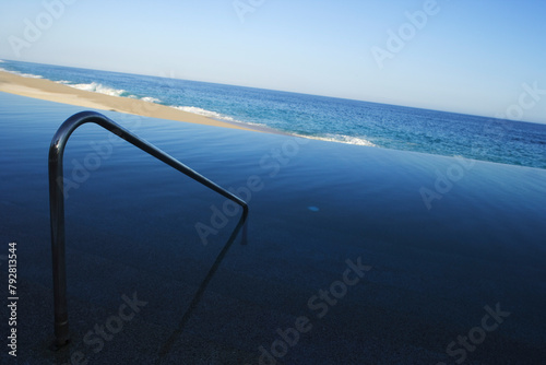 The solitary metal handrail on an empty pristine beach captivates the sense of solitude and contemplation against the ocean backdrop photo