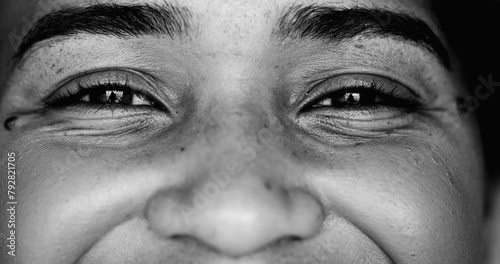 One young black woman smiling at camera, intense macro close-up detail person of African descent staring at camera with friendly happy demeanor in monochrome