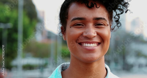 One happy young black Brazilian woman laughing and smiling standing outside in urban environment. Portrait of joyful person authentic friendly expression