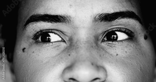 One paranoid worried young black woman macro close-up eyes looking sideways with intense preoccupation and obsession in dramatic black and white monochrome