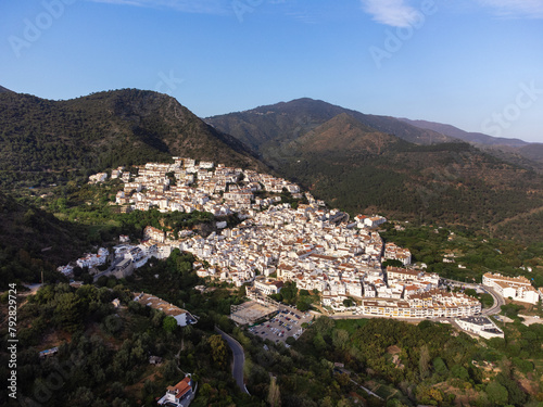 Drone shot over Ojen, Spain showcasing the white buildings nestled in the green hills of Andalusia