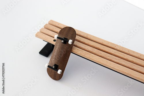 Blank wooden fingerboard at wooden bench on the white background. Mini skateboard, small skateboard deck
