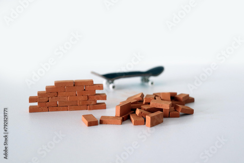 Mini red miniature bricks with wooden fingerboard in the background. Mini skateboard, small skateboard deck