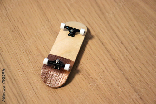 Wooden fingerboard at the ramp on table, close up. Mini skateboard, small skateboard deck