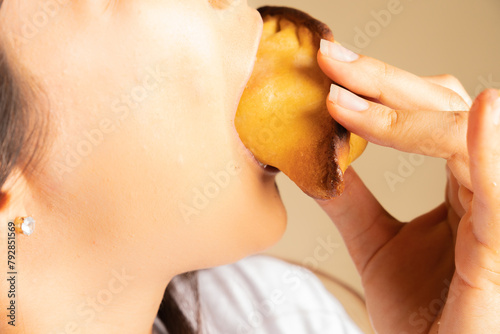 unrecognizable young woman approaching to bite into a snack, empanada, salteña, enjoying food happily
