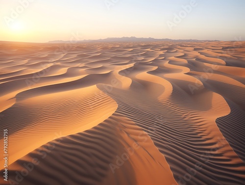 Aerial view of sand dunes in a desert at sunset, ripples and patterns highlighted by the low light, vast and untouched landscape