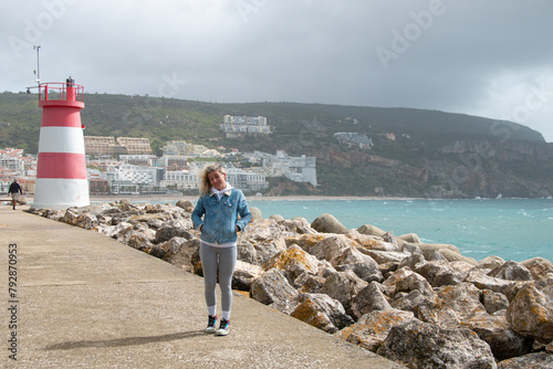 Casually dressed blonde woman poses on a pier next to the sea on a cloudy day photo