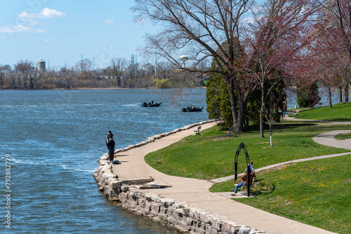 Fishermen, Boats, And People Enjoying The Fox River In De Pere, Wisconsin, In Spring photo