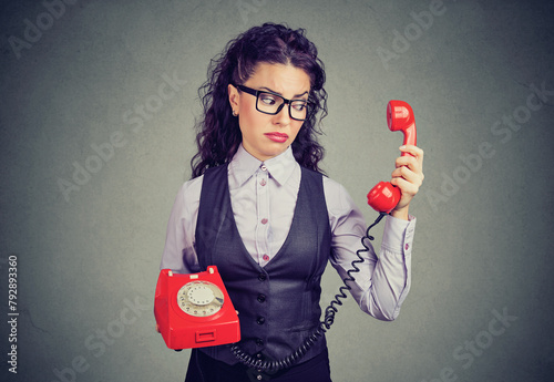 Young business woman looking at a red phone with a suspicious expression