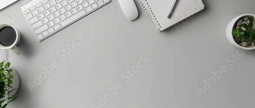 Photo of a modern office desk with a white keyboard, mouse and notebook on a grey background. photo