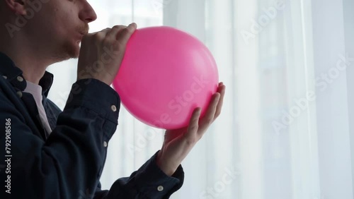 The guy inflates a pink balloon.
Pink balloon photo