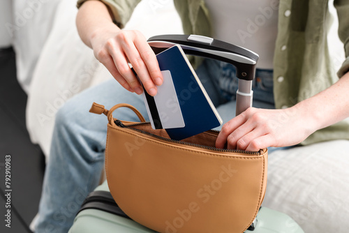 Young woman putting passport and credit card in her purse before traveling abroad. Summer holidays.