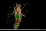 Intensity of a training session. Dynamic energy of muscular man training shirtless, jumping rope on black background with stroboscope effect. Concept of sport, active and healthy lifestyle, endurance