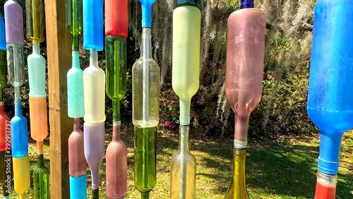 Wall made of colorful old bottles in a field of green grass and trees