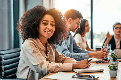 Portrait of african american business lady turning to camera while visiting business conference with couch. Enthusiastic woman making remarks in notebook for keeping valuable information.