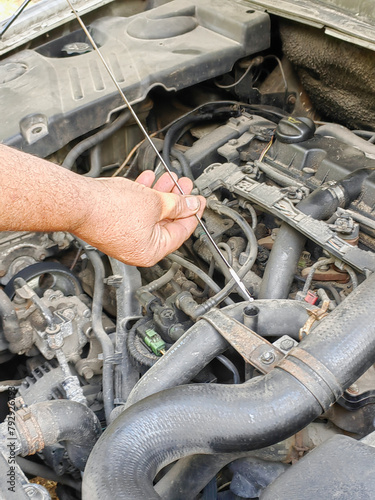a man repa man repairs a car by checking the oil level with a dipstickairs a car by checking the oil level with a dipstick