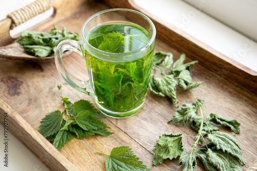 Herbal tea made of dry Urtica dioica, known as common nettle, burn nettle or stinging nettle leaves in clear glass cup. In home kitchen by the window.