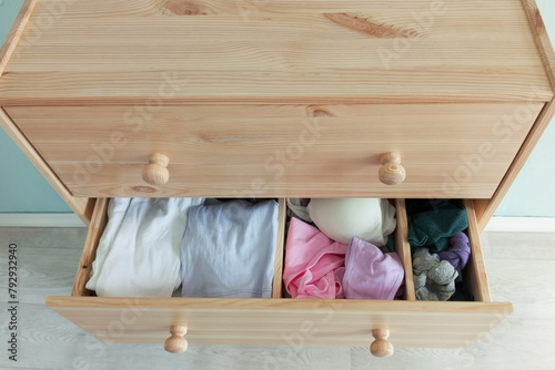 Open drawer with clothes of a wooden chest of drawers. View from above.