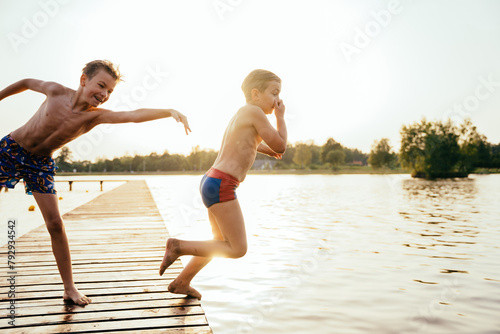 A boy pushes his friend before jumping from a bridge into a lake photo