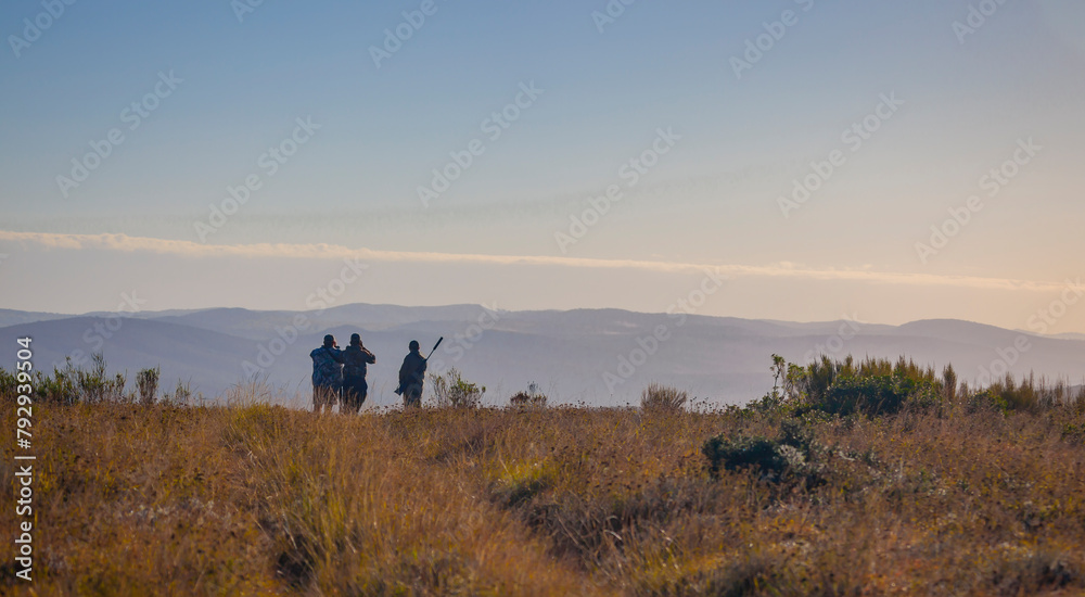 Silhouettes of hunters in the morning landscape of the African savannah.