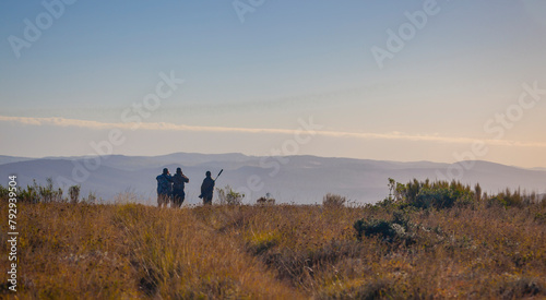 Silhouettes of hunters in the morning landscape of the African savannah.