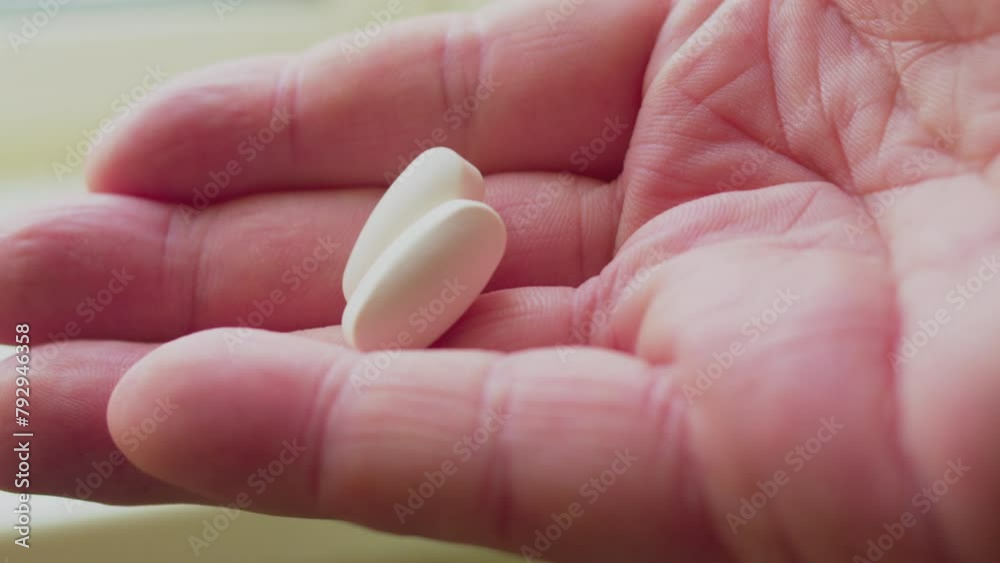 Health and medicine. Hand holds a large white capsule. Close-up. Health and medicine. Hand holds a large white capsule. Close-up.