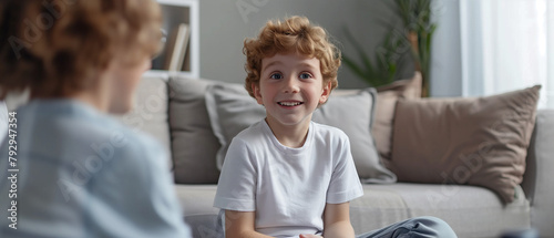 appy little child communicating with psychologist sitting on sofa during therapy session at home