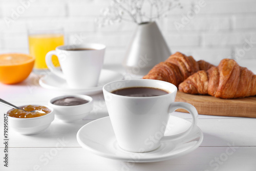 Cup of coffee, jam and croissants on white wooden table. Tasty breakfast