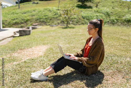 Focused female freelancer using laptop to work remotely in park