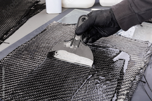 hand working epoxy resin into woven carbon fiber reinforcement cloth. Production manufacturing of  hand laminating CFK composite sheet material.