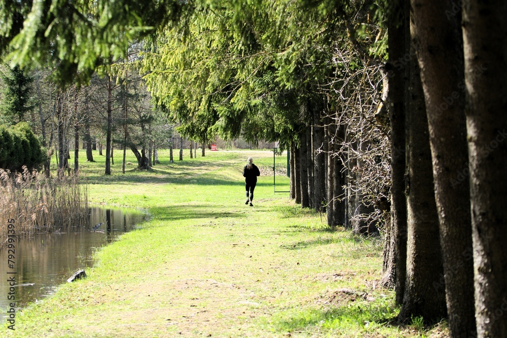 a young girl is doing a morning jog on a sunny day along a park path