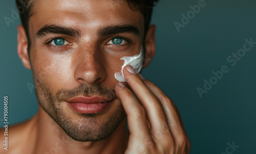 Close up young handsome man applying white skin care cream to his face, concept of male grooming failure and taking care of his skin