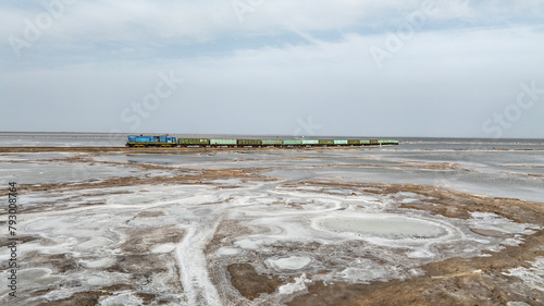 a train travels across a salt lake to transport salt in the area of Lake Baskunchak on a spring day