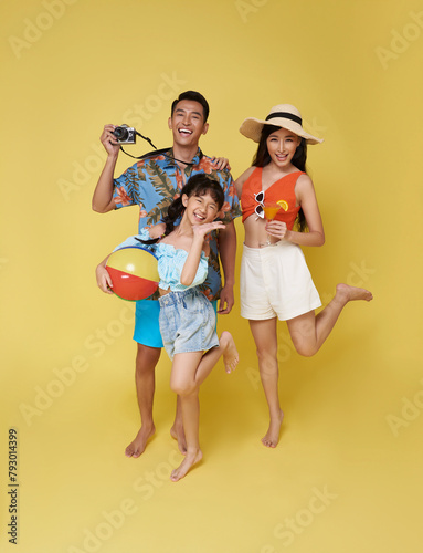 Happy fun asian family vacation portrait. Father, mother and daughters enjoying summer beach isolated on yellow studio background.