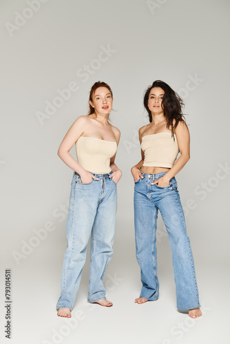 A loving lesbian couple in elegant attire happily posing together in jeans.