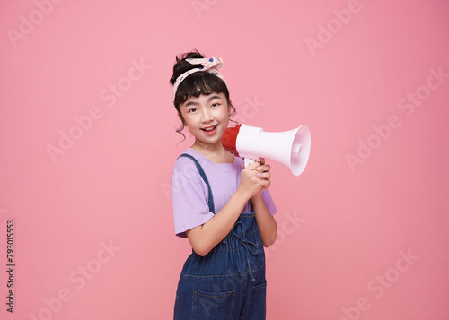 Asian little girl standing and holding megaphone isolated on pink background, Speech and announce concept
