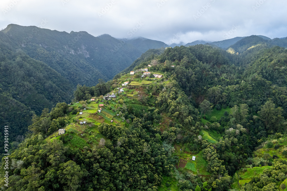 Fototapeta premium Madeira Island landscape, small village on hills and green lush forest. Aerial drone view. Portugal travel.