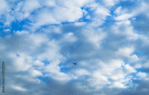 The helicopter is flying high in the sky backdrop of clouds
