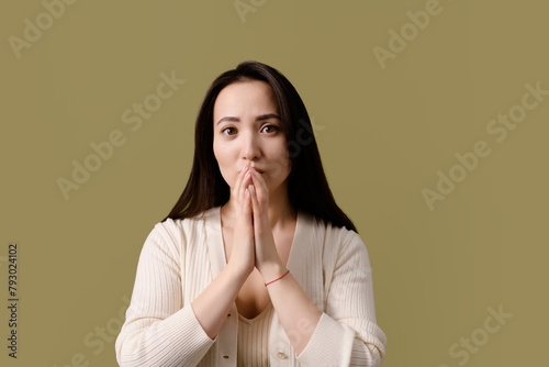Scared asian woman looking at camera isolated on green 